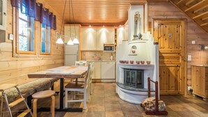 A cozy log cabin interior with a dining area, kitchen, and fireplace.