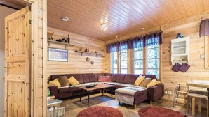 A cozy wooden cabin interior with a sofa, coffee table, and two round rugs.