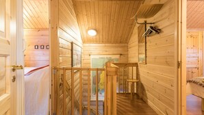 A wooden cabin interior with a staircase leading to a loft bedroom.