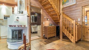 A wooden interior with a fireplace, kitchen, and a wooden staircase.