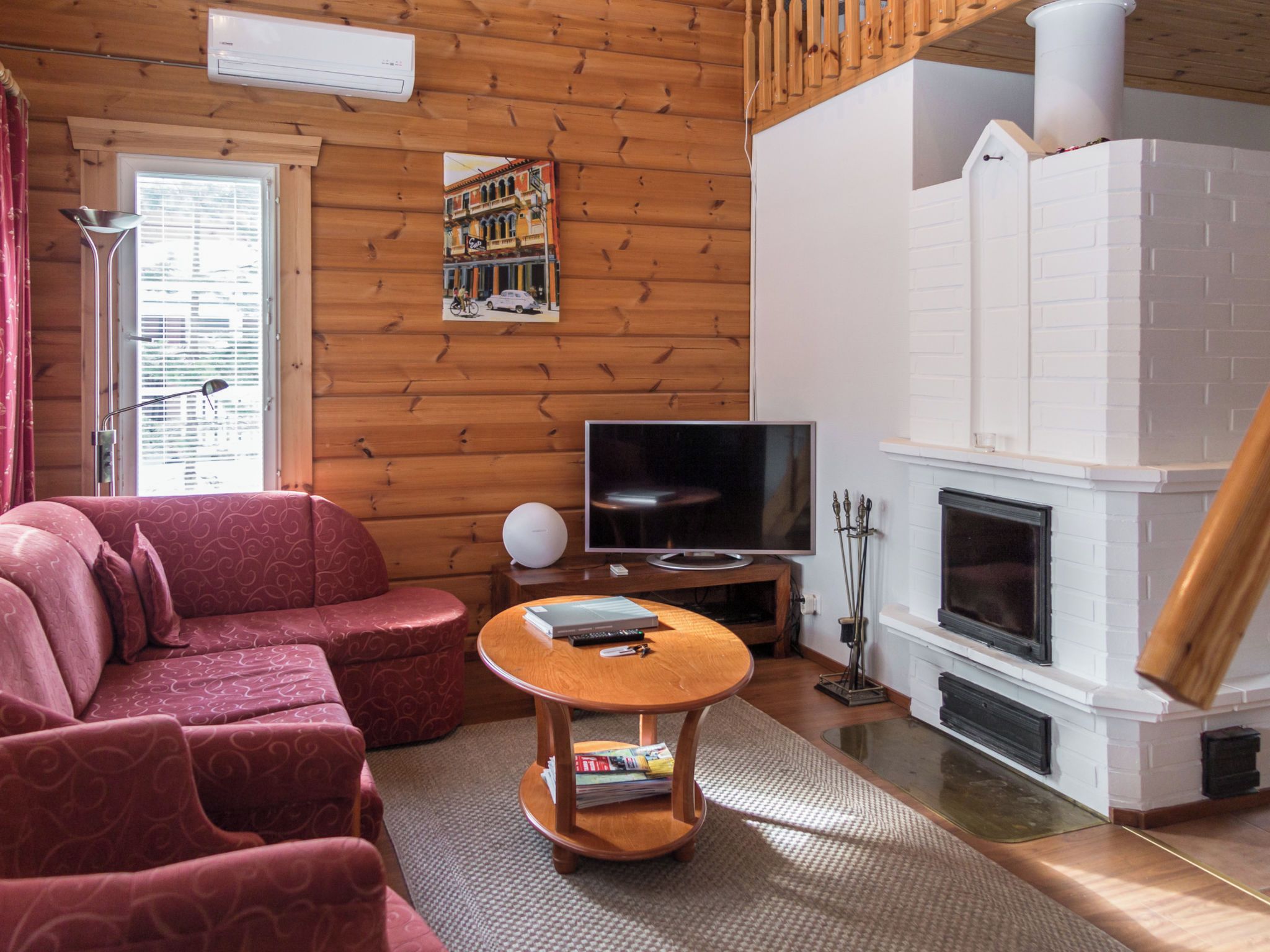 Ein gemütliches Wohnzimmer mit einer Couch, einem Fernseher, einem Kamin und einer Holzwand.