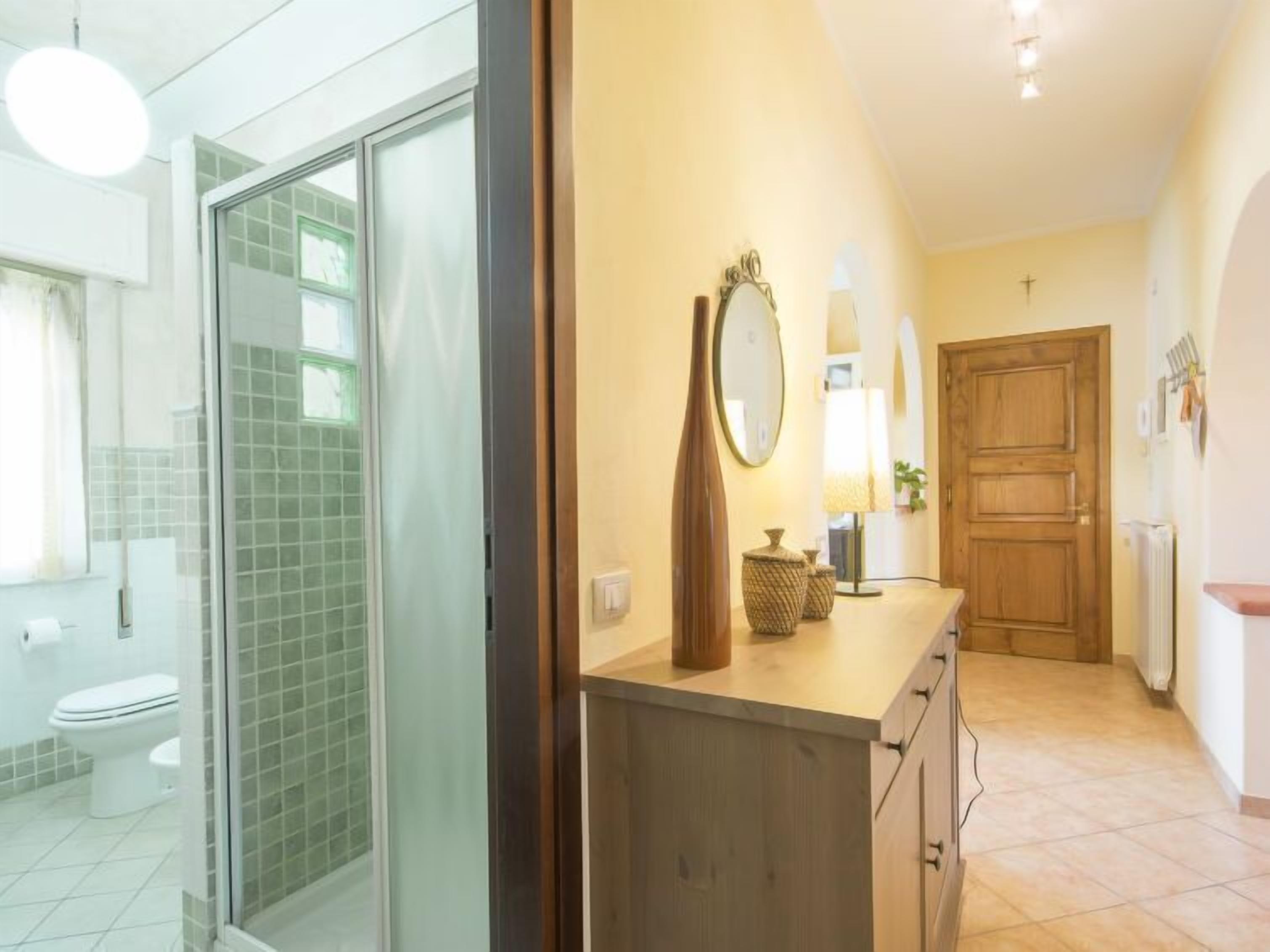 Ein modernes Badezimmer mit einer Duschkabine aus Glas, einem Holzausleger mit Spiegel und einem gefliesten Boden.