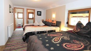 Un dormitorio con dos camas, una ventana y una puerta que da a un baño.