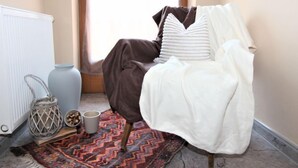 Un dormitorio acogedor con cama, un radiador, una ventana y un tapete estampado.