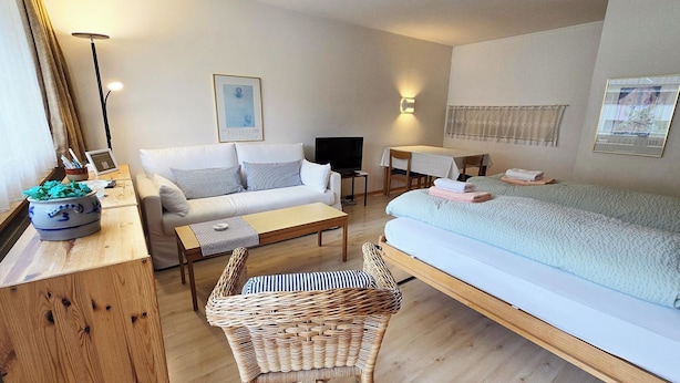 Una camera d'albergo accogliente con un letto, una poltrona, un tavolo da pranzo e una sedia in vimini.