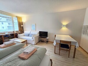 A living room with a sofa, a TV, a table, and a bookshelf.