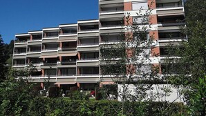 Un edificio a più piani con balconi, tetto piatto e facciata in mattoni e bianco.