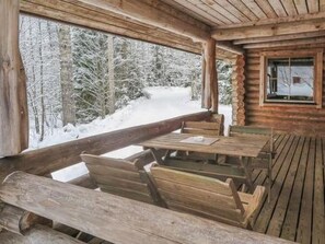 Guests can enjoy seating on the covered porch with benches and a table.
