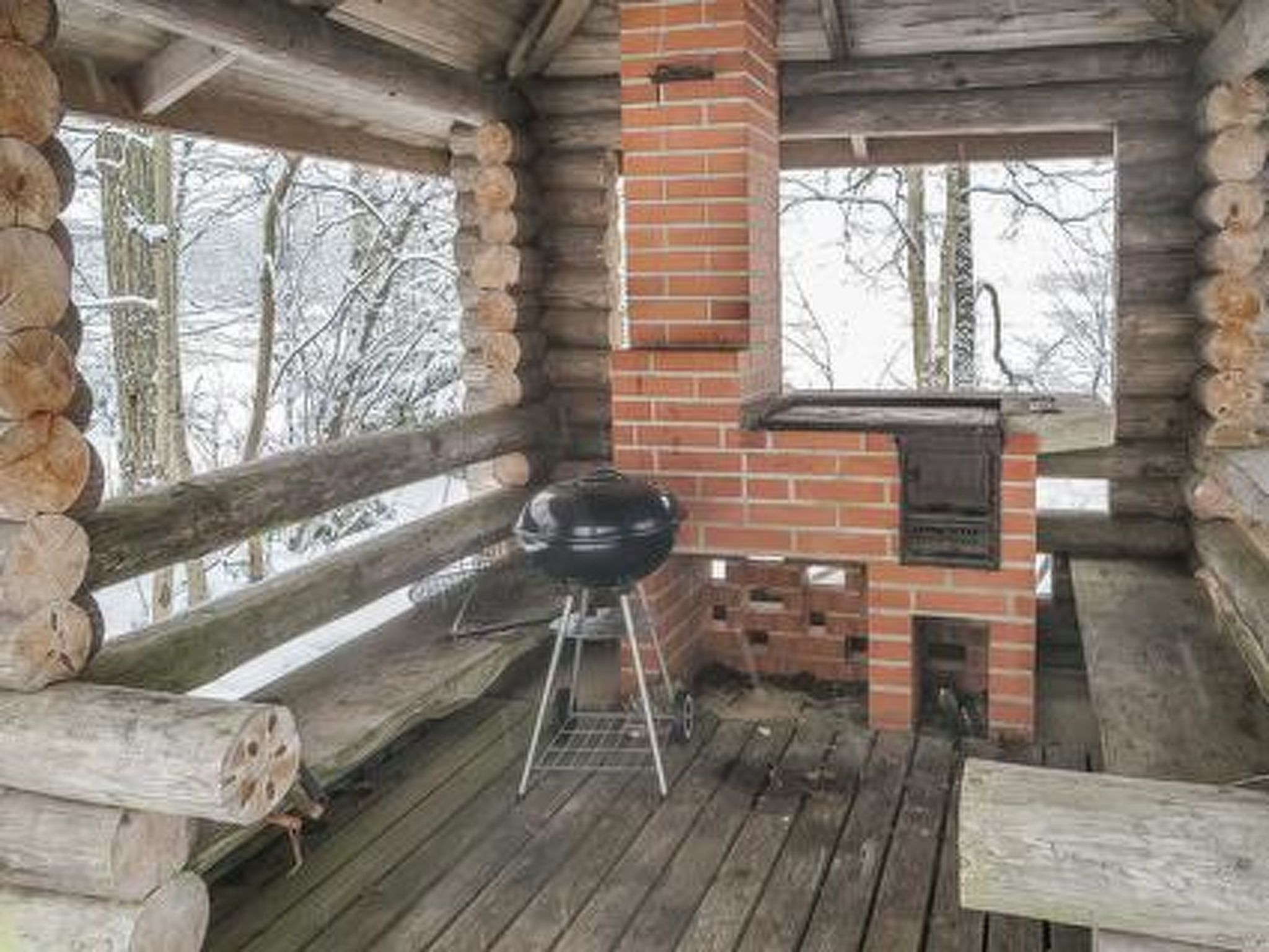 Eine Blockhütte mit Kamin aus Ziegeln und Grill vor der Tür.