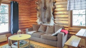 A log cabin interior with a sofa, a small round table, and a window with curtains.