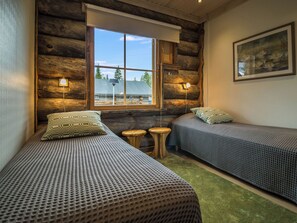 Una habitación tipo cabaña con dos camas, una ventana y un cuadro en la pared.