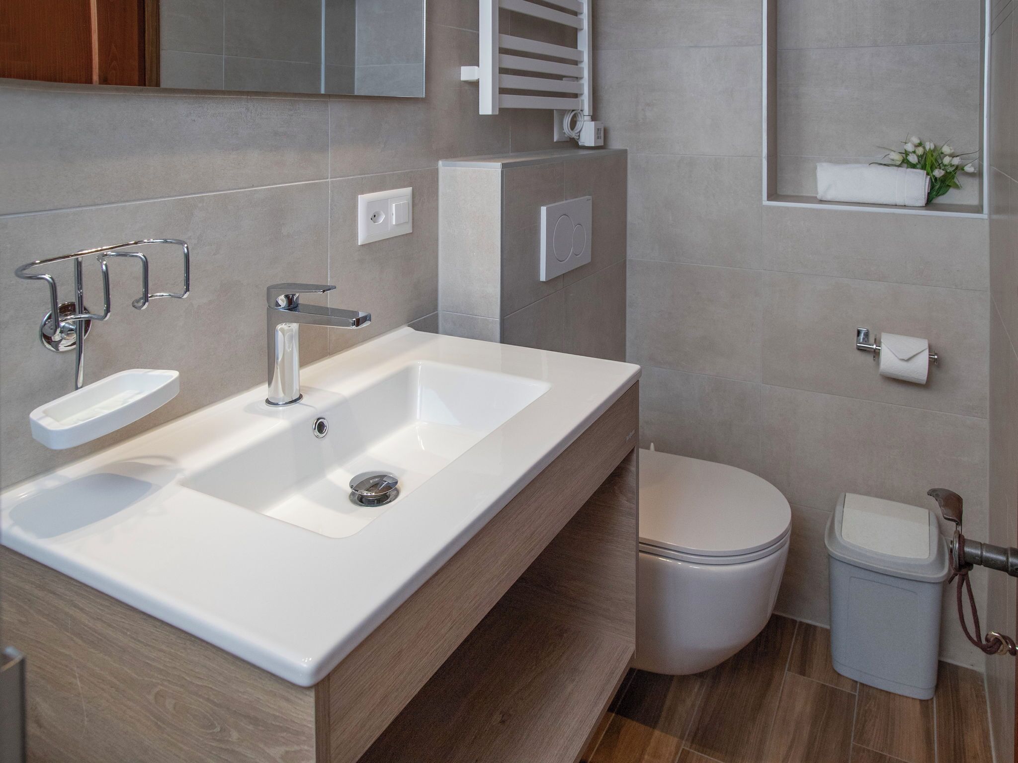 A modern bathroom with a white sink, chrome faucet, and a toilet.