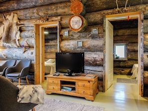 A log cabin interior with a television on a wooden stand, a chair, and a fireplace. - Villa mitja by Interhome (Posio)