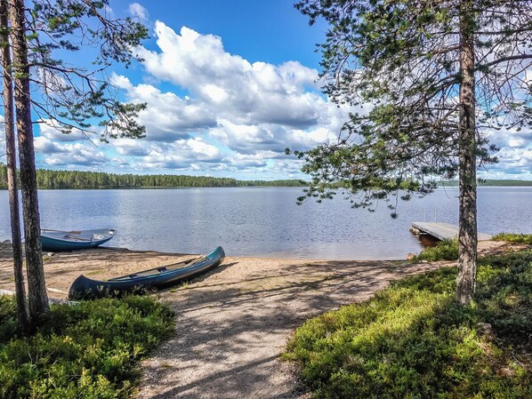 A lakeside view with boats, trees, and a clear sky.