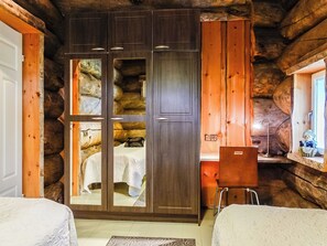 A log cabin room with a large wardrobe, a bed, and a small table.