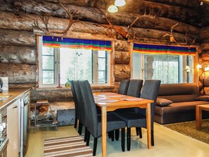 A log cabin interior with a dining table, chairs, a sofa, and a kitchen area. - Villa mitja by Interhome (Posio)