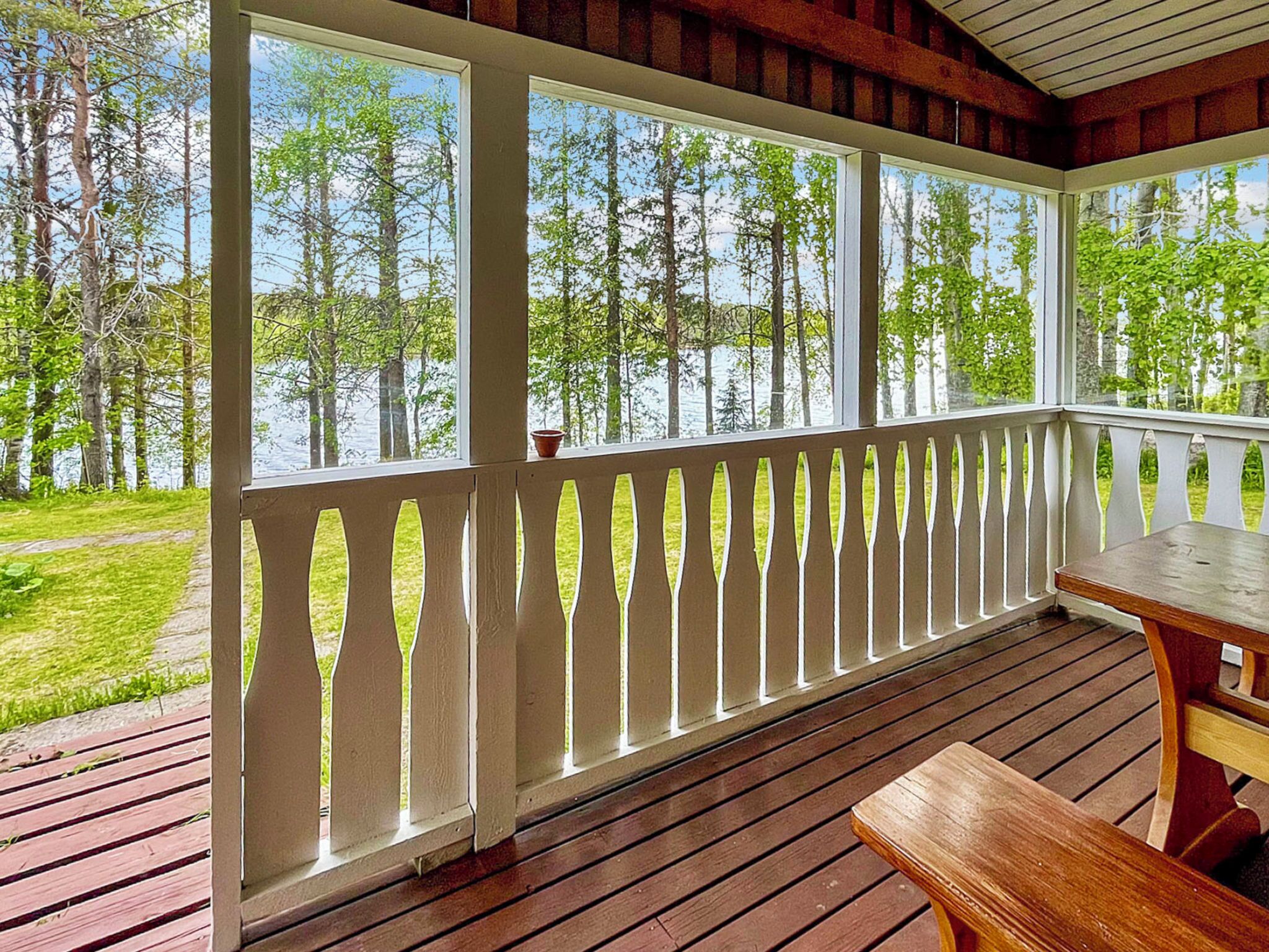 Una terraza de madera con barandilla blanca, una mesa y bancos.