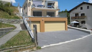 Ein zweistöckiges Gebäude mit Garage, Balkon und einer Treppe zum Obergeschoss.