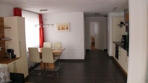 Ein moderner Wohnraum mit Essbereich, Küche und einem Flur zu einem weiteren Zimmer.