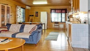Un intérieur de chalet chaleureux comprenant un salon, un coin repas et une cuisine.