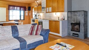 Un intérieur de chalet chaleureux comprenant un espace de vie, un plafond en bois, une cuisine et une cheminée.