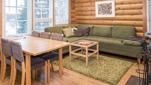 Ein gemütliches Blockhaus-Interieur mit einem Holzespeisetisch, einem grünen Sofa und einem Bild an der Wand.