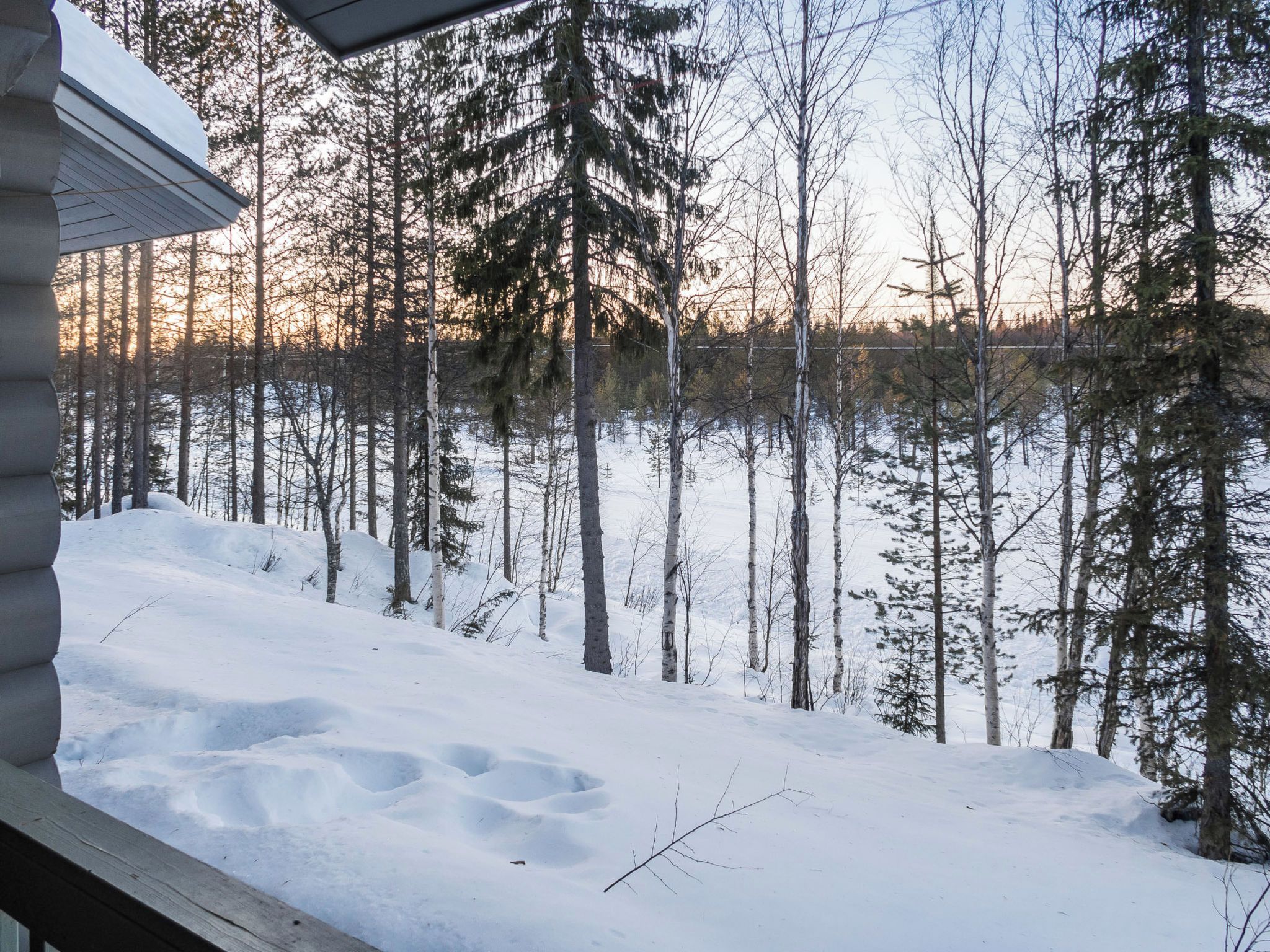 A cabin with a snow-covered ground and a forest in the background.