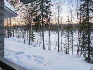A cabin with a snow-covered ground and a forest in the background.