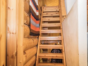 Una escalera de madera que conduce a una zona superior con una manta a rayas colgada en la pared.