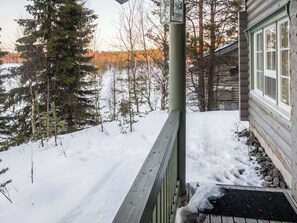 Una terraza de madera con un sendero nevado que lleva a una cabaña.