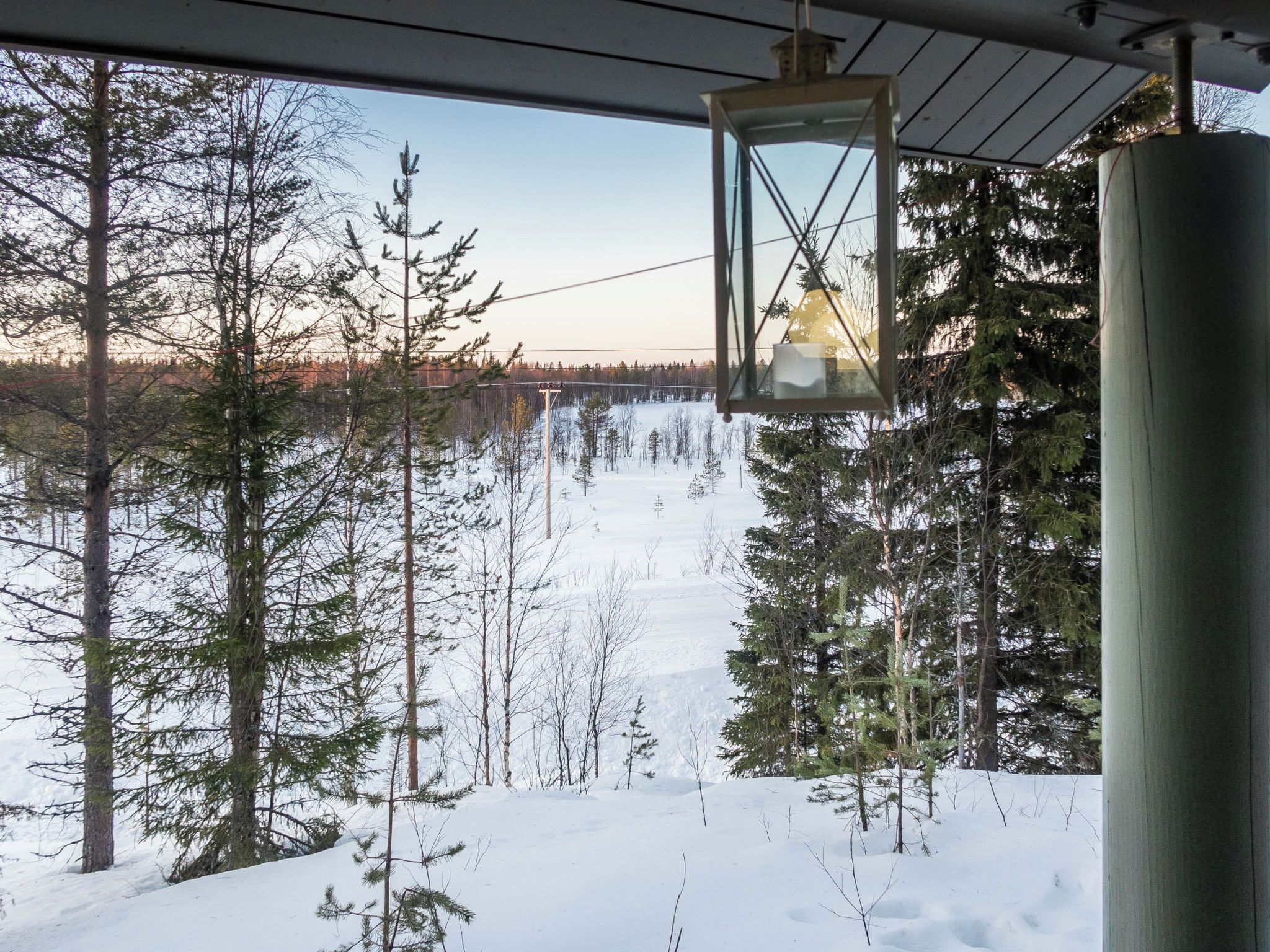 A snowy landscape with a cabin and a clear view of a bridge in the distance.