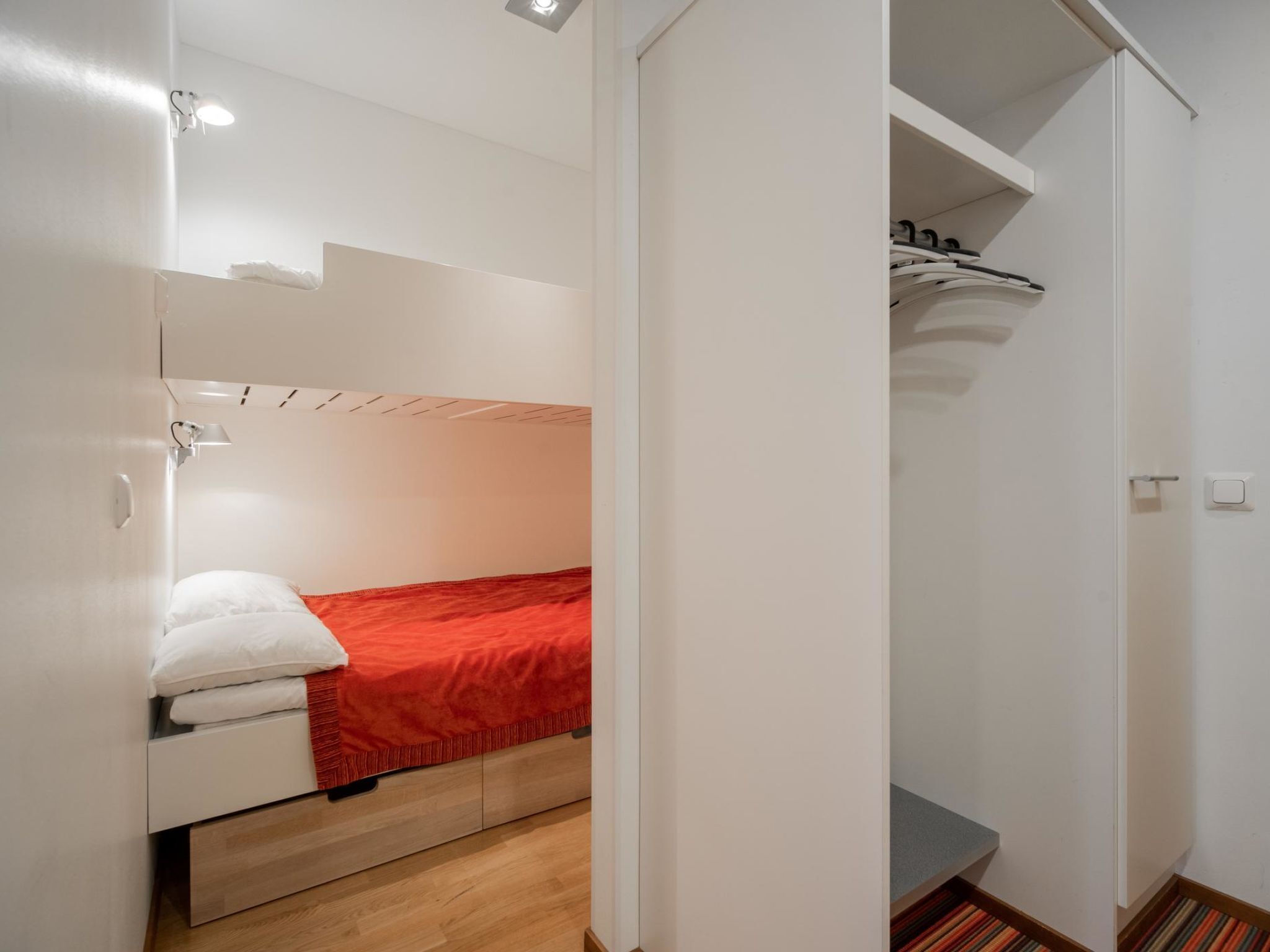 Camera d'albergo compatta con un letto, un armadio e un piccolo angolo salotto.