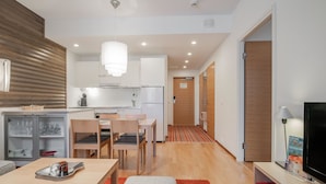 Un appartement moderne comprenant une cuisine, un coin repas et un salon. Il est équipé d’une table à manger avec des chaises, d’un canapé, d’une télévision et d’une bibliothèque.