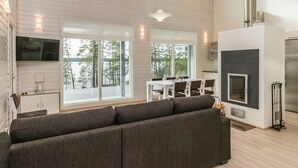 A spacious living area with a large gray sectional sofa, a dining table with chairs, and a kitchen area with a stove and refrigerator.