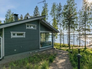 Een huis met een groot raam, een schoorsteen en uitzicht op een meer.