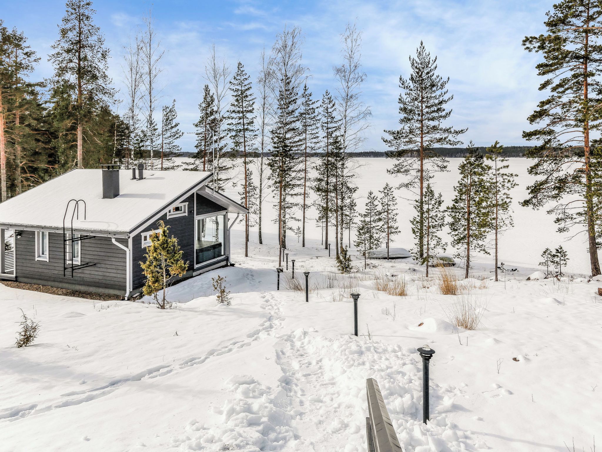 Eine Hütte inmitten einer schneebedeckten Landschaft, umgeben von Bäumen.