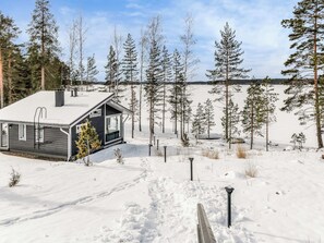 Una cabaña en un paisaje nevado, rodeada de árboles.