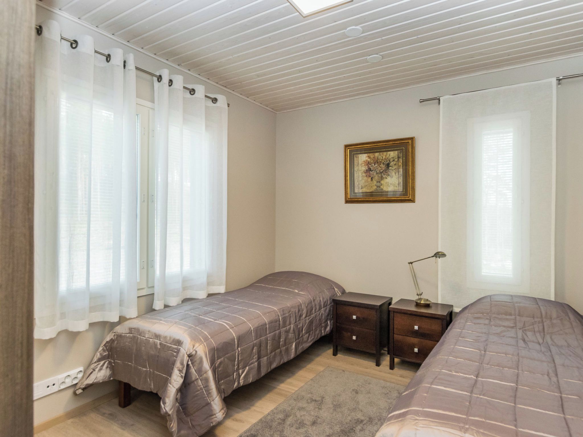 Ein Schlafzimmer mit zwei Betten, einem Nachttisch, einer Lampe und einem Bild an der Wand.