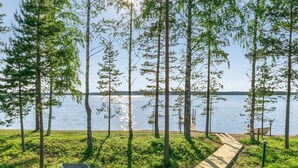 A pathway leading to a dock by a lake, surrounded by trees and greenery.