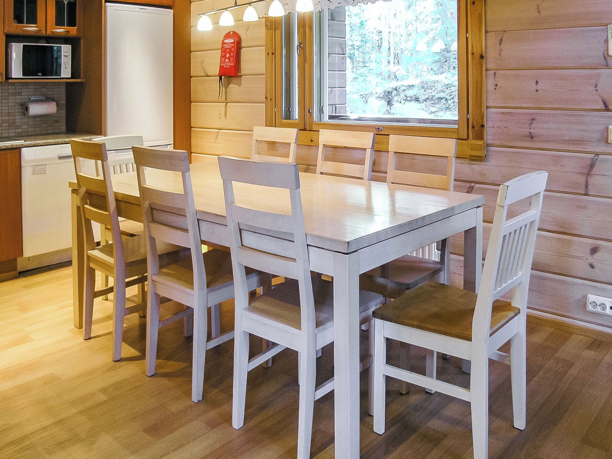 A wooden interior with a dining table and chairs, a kitchen area with a microwave, and a fire extinguisher on the wall.