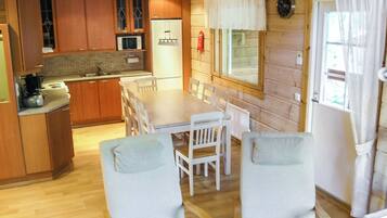 Cocina compacta con armarios de madera, microondas y comedor con mesa y sillas.