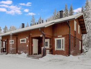 A wooden cabin with a covered porch, a ladder, and a fire extinguisher.