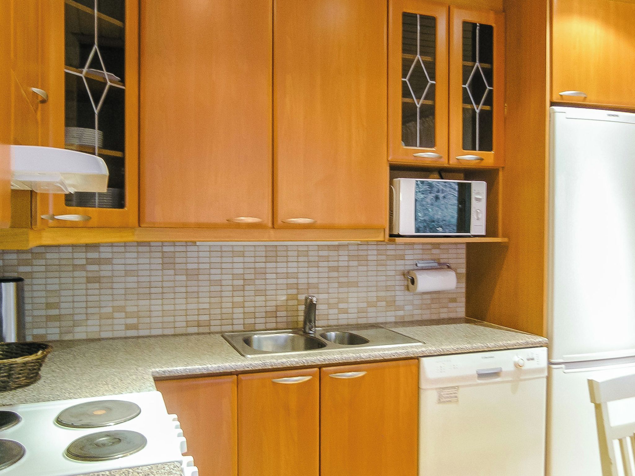 Une cuisine avec des meubles de rangement en bois, un four à micro-ondes, un évier et une cuisinière.
