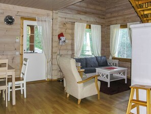L’intérieur d’un chalet accueillant, avec un plancher en bois, un canapé, une table à manger et une chaise.
