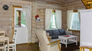 A cozy cabin interior with a wooden floor, a sofa, a dining table, and a chair.