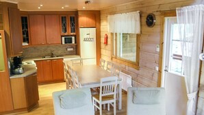 A cozy kitchen with wooden cabinets, a microwave, and a dining area with a table and chairs.