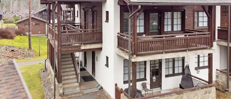A two-story building with a balcony, a staircase, and a stone foundation.