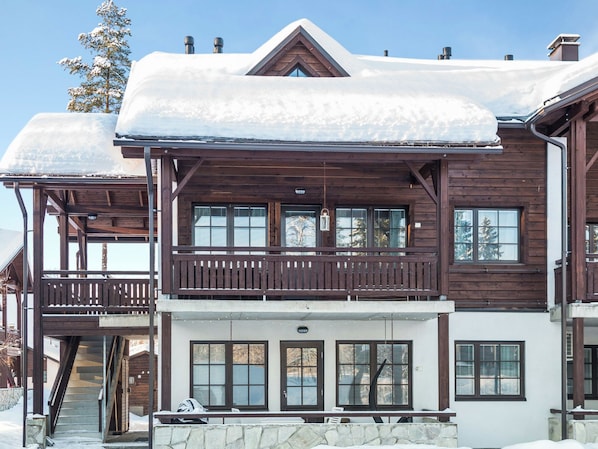 A two-story wooden lodge with a balcony and a stone foundation.