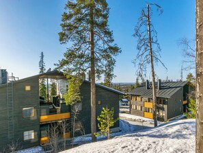 A modern cabin-style building with a sloped roof, large windows, and a visible deck area.