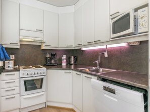 A compact kitchen with white cabinets, a built-in oven, a dishwasher, a microwave, and a coffee maker. - Karhunvartijan kota b1 by Interhome (Kuusamo)